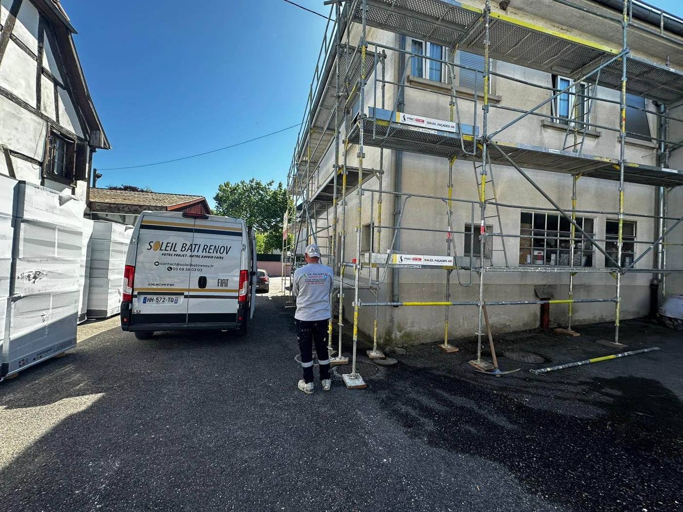 Vue d'ensemble chantier façade : van SBR, échafaudage et isolants